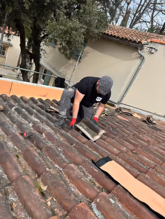 Couvreur reposant une tuile canal sur une toiture ancienne